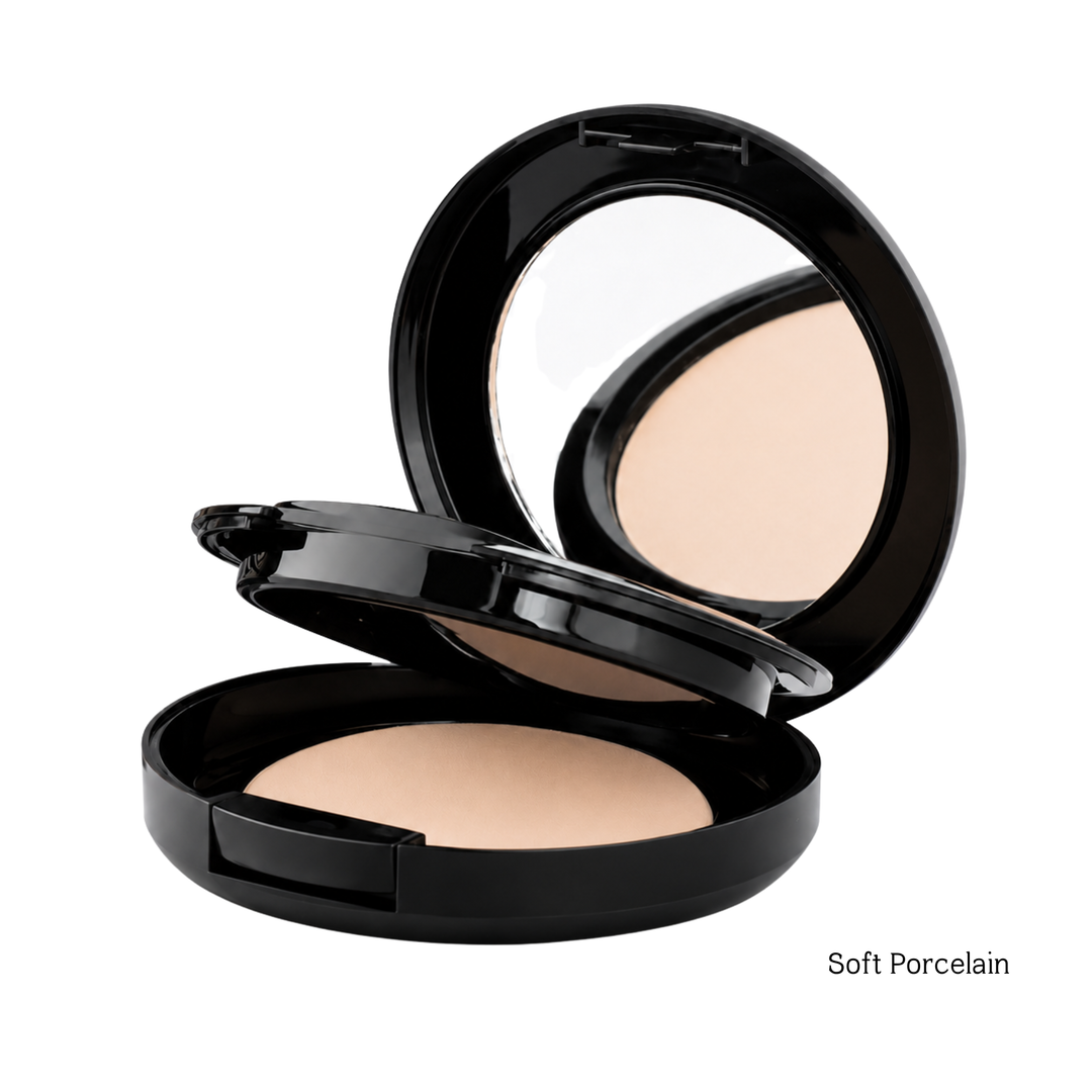 An open black round compact powder with a mirror on the lid and the pressed powder visible in the compact. The text 'Soft Porcelain' appears in the bottom right corner on a white background.