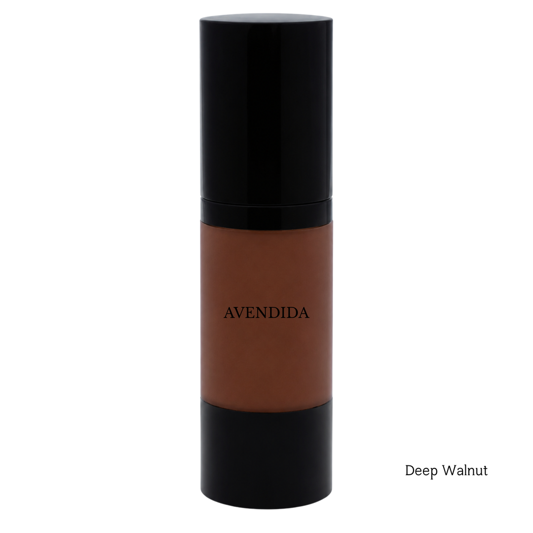 A bottle of AVENDIDA liquid foundation in the shade Deep Walnut, featuring a deep brown liquid visible through a clear cylindrical bottle with a glossy black cap and base, set against a plain white background.