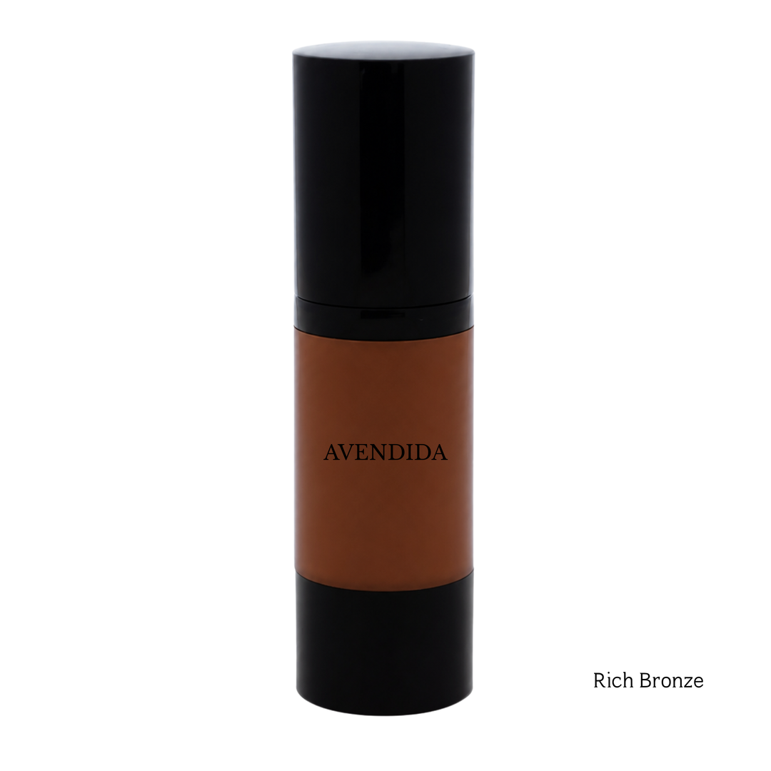 A bottle of AVENDIDA liquid foundation in the shade Rich Bronze, featuring a warm brown liquid visible through a clear cylindrical bottle with a glossy black cap and base, set against a plain white background.