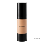 A bottle of Avendida liquid foundation in the shade Soft Sand, featuring a black cap and base with a clear center showing the beige foundation formula, set against a plain white background.