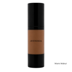 Load image into Gallery viewer, A bottle of AVENDIDA liquid foundation in the shade Warm Walnut, featuring a warm brown liquid visible through a clear cylindrical bottle with a glossy black cap and base, set against a plain white background.